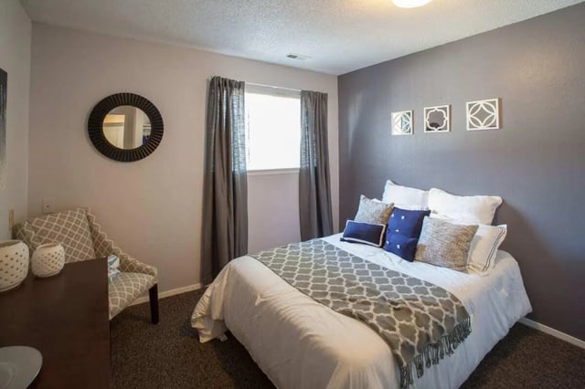 Bed with patterned blanket mirror and armchair bedroom at Hawks Pointe II in Lawrence Student Accommodation