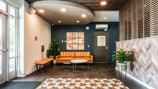 Orange sofa, two coffee tables, plants, bench Living room at The Vista Apartments in Boise Student Accommodation