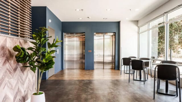 Two elevators chairs tables and plant lobby at The Vista Apartments in Boise Student Accommodation