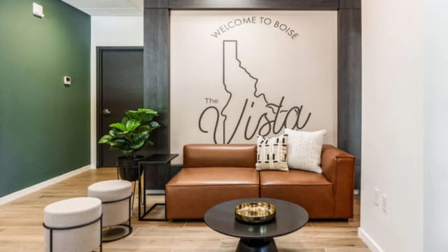 Brown sofa pillows plant welcome Boise wall living room at The Vista Apartments in Boise Student Accommodation