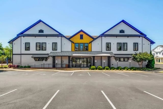 Modern building with blue roof and parking lot exterior at The Collective At Auburn in Auburn Student Accommodation