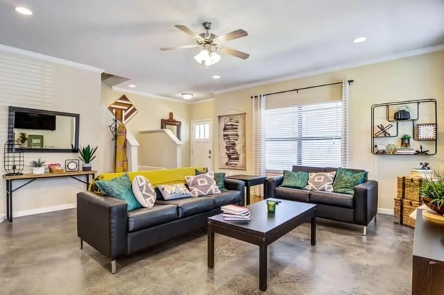 Black sofas with pillows and yellow throw living room at The Collective At Auburn in Auburn Student Accommodation