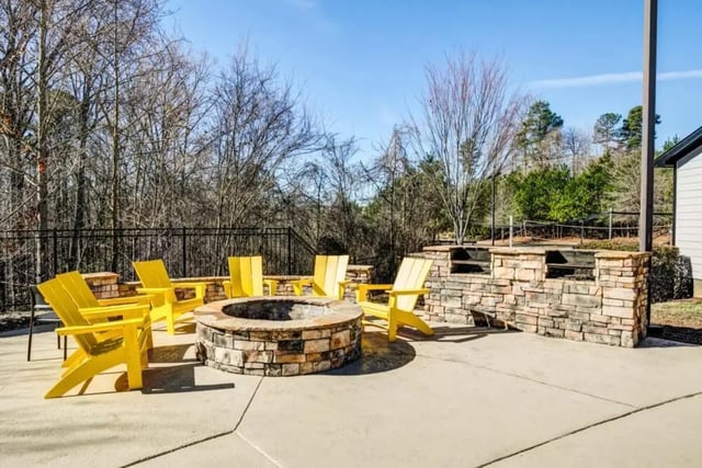 Yellow chairs around stone fire pit exterior at The Collective At Clemson in Clemson Student Accommodation