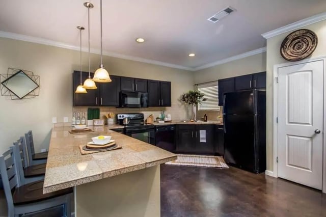Kitchen island black cabinets black refrigerator kitchen at The Collective At Clemson in Clemson Student Accommodation
