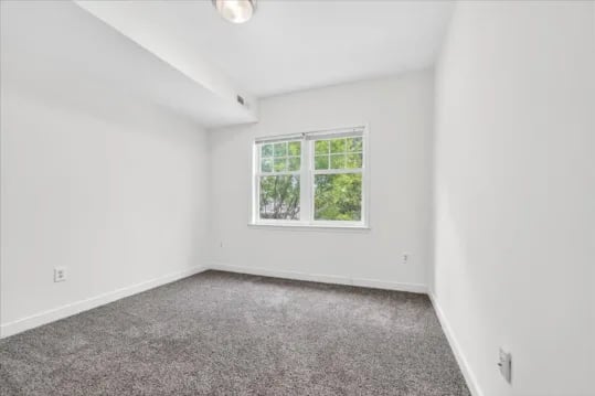 Empty white room with grey carpet and window bedroom at Wertland Square in Charlottesville Student Accommodation