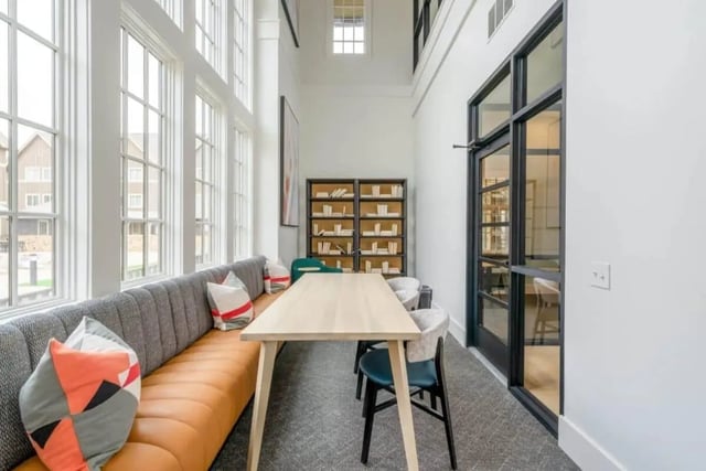 Upholstered bench table chairs bookshelves and windows common area at The Collective At Lubbock in Lubbock Student Accommodation