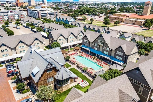 Apartment complex with swimming pool and lounge chairs exterior at The Collective At Lubbock in Lubbock Student Accommodation