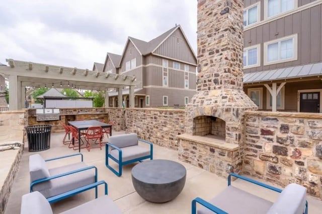 Outdoor patio with grill fireplace seating and dining area exterior at The Collective At Lubbock in Lubbock Student Accommodation
