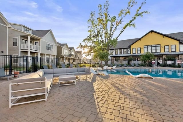 Grey sectional sofa lounge chairs and pool exterior at The Collective At Norman in Norman Student Accommodation