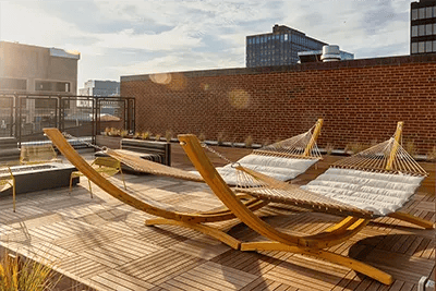 Hammocks on rooftop deck with brick wall exterior at The Archive in New Haven Student Accommodation