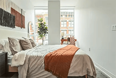 Bed with orange throw desk and plant bedroom at The Archive in New Haven Student Accommodation