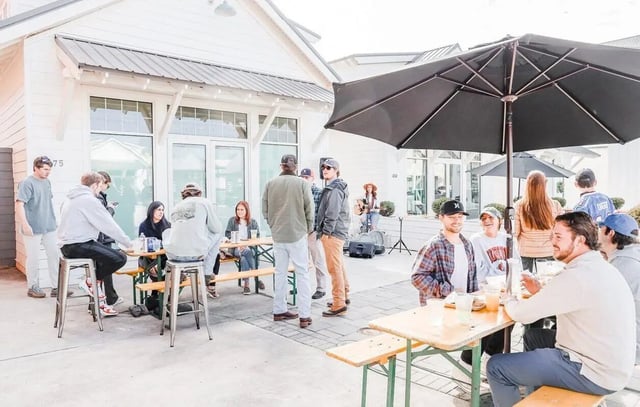 People gathered at outdoor tables under umbrella exterior at Midtown Auburn in Auburn Student Accommodation