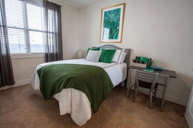 Bed with green blanket desk chair artwork bedroom at The Waverly in Newark Student Accommodation