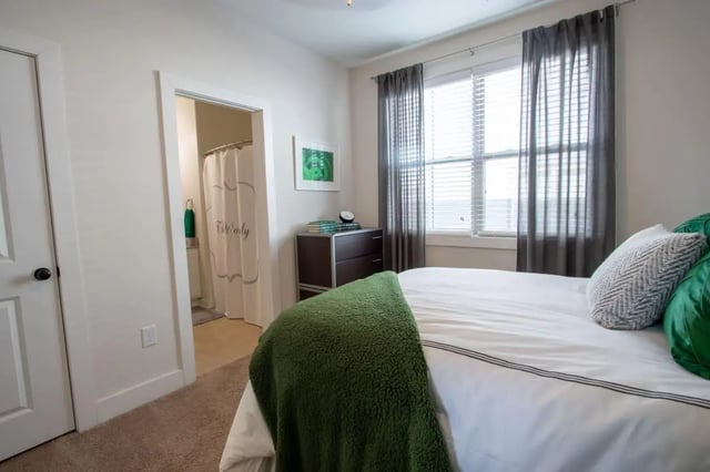 Bed with green blanket and bathroom visible bedroom at The Waverly in Newark Student Accommodation