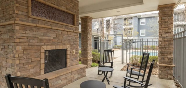 Stone fireplace chairs tables pool exterior at The Connection at Lawrence in Lawrence Student Accommodation