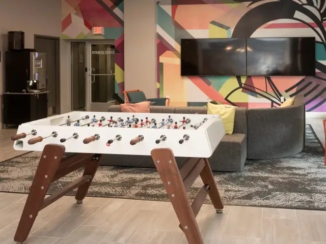 Foosball table sofa TVs colorful wall living room at SoCam 290 Apartments in New Brunswick Student Accommodation