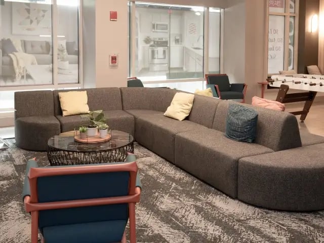 Gray sectional sofa coffee table chairs game table living room at SoCam 290 Apartments in New Brunswick Student Accommodation