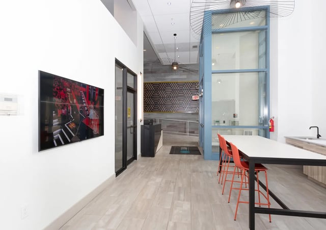 Large screen television orange chairs and counter area communal area at SoCam 290 Apartments in New Brunswick Student Accommodation