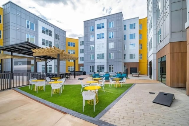 Courtyard with yellow tables white chairs and lounge area exterior at Proximity At 10th in Greenville Student Accommodation