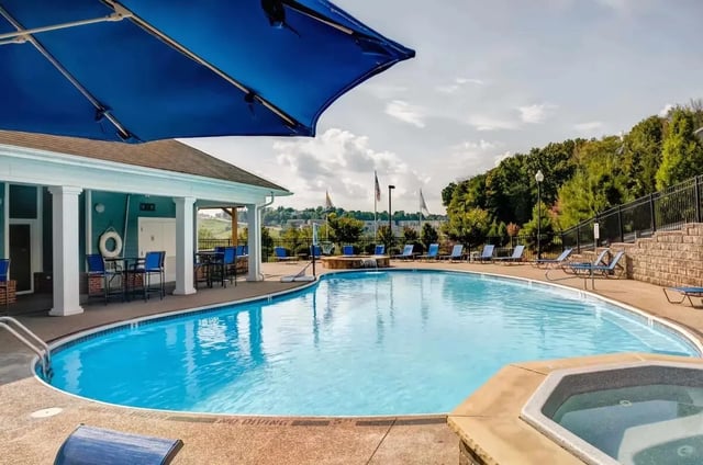 Blue umbrella lounge chairs building pool spa outdoor area at West Run Morgantown in Morgantown Student Accommodation