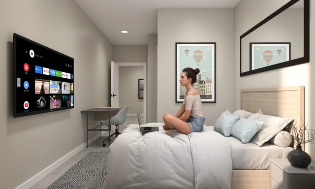 Woman on bed with laptop and wall mounted TV bedroom at Villas Knoxville in Knoxville Student Accommodation