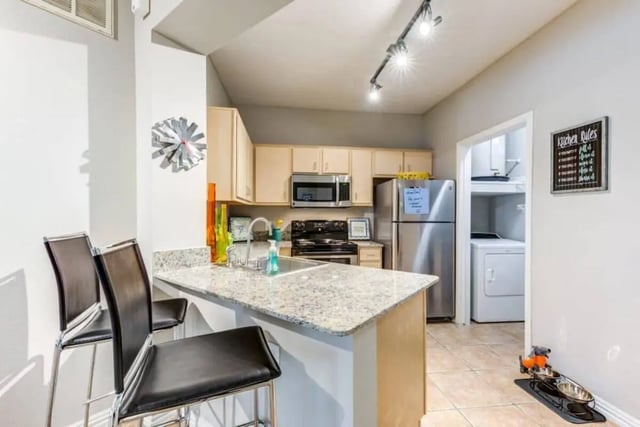 Kitchen with counter chairs refrigerator and washer dryer kitchen at Villas On Guadalupe in Austin Student Accommodation