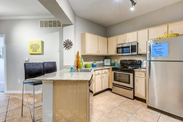 kitchen with stainless steel appliances bar stools and counter kitchen at Villas On Guadalupe in Austin Student Accommodation