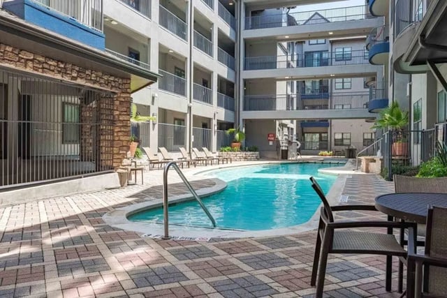 Swimming pool with lounge chairs and tables exterior at Villas On Guadalupe in Austin Student Accommodation