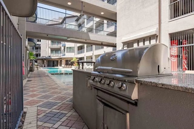 BBQ grill by pool with apartment buildings exterior at Villas On Guadalupe in Austin Student Accommodation