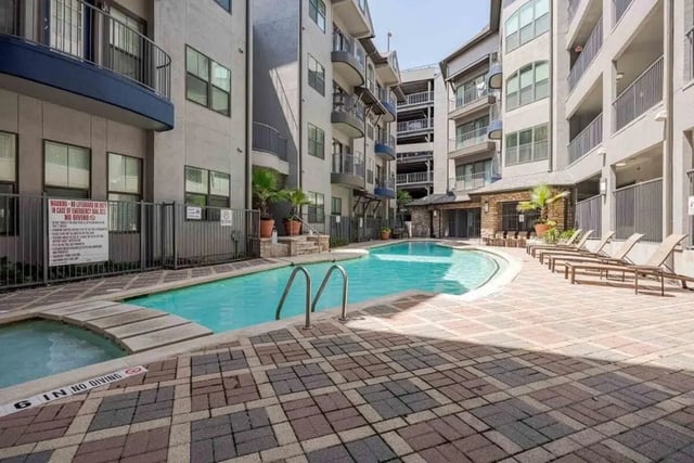 Pool with lounge chairs and surrounding buildings exterior at Villas On Guadalupe in Austin Student Accommodation