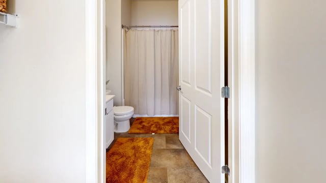 Toilet sink shower curtain orange rugs bathroom at The Hill at Rochester in Rochester Student Accommodation