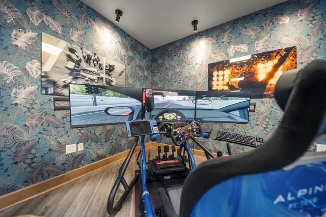 Racing simulator with triple monitors and floral wallpaper gaming room at The Hill at Rochester in Rochester Student Accommodation