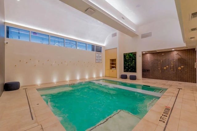 Indoor swimming pool with showers and seating area at Villas on Rio in Austin Student Accommodation
