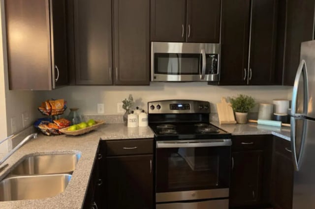 Dark cabinets stainless steel microwave stove and refrigerator kitchen at The Pavilion at North Grounds Apartments in Charlottesville Student Accommodation
