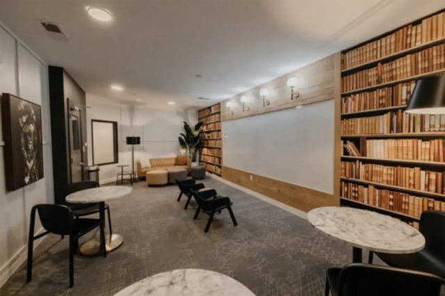 Seating tables artwork and a bookshelf living room at The Pavilion at North Grounds Apartments in Charlottesville Student Accommodation