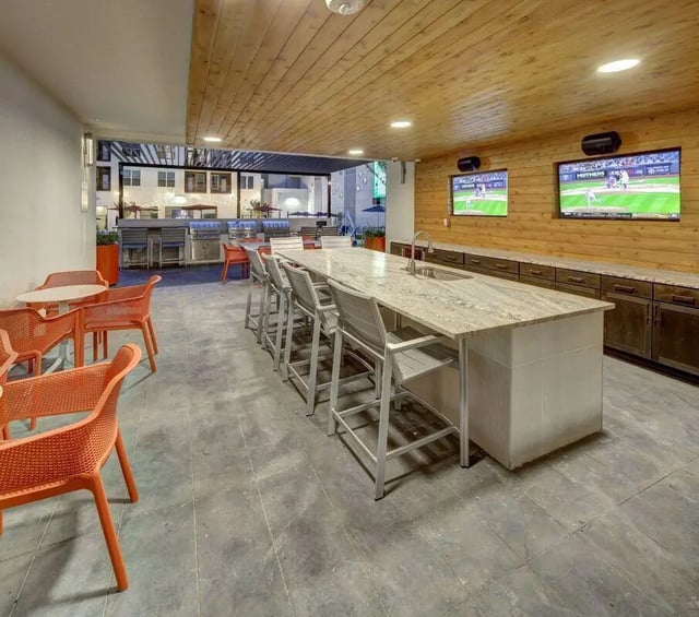 Island counter bar stools and TVs outdoor kitchen living room at The Lyndon in San Marcos Student Accommodation