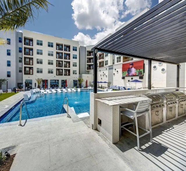 Grill station, bar seating, pool, lounge chairs, exterior living area. at The Lyndon in San Marcos Student Accommodation