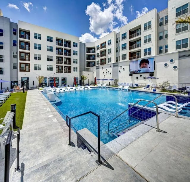 Large pool with lounge chairs and building exterior poolside at The Lyndon in San Marcos Student Accommodation