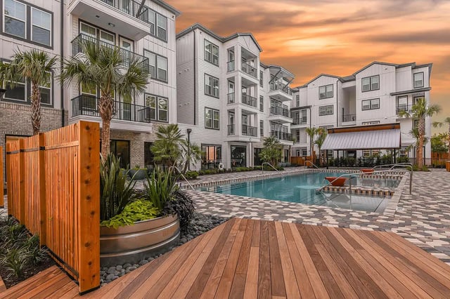 Pool lounge area with building and palm trees exterior at Aero on 24th in Gainesville Student Accommodation
