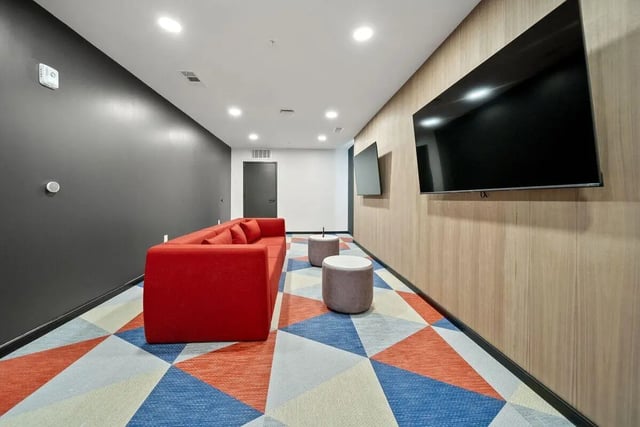Red sofa with two ottomans and televisions living room at The Hive in Atlanta Student Accommodation