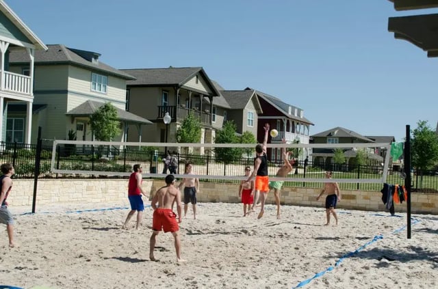 Volleyball game players in shorts on sand court playing area at The Cottages of College Station in College Station Student Accommodation