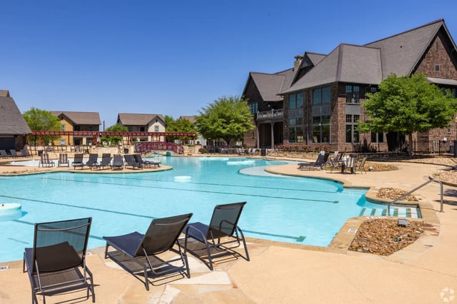 Deck chairs by a large resort-style swimming pool exterior at The Cottages of College Station in College Station Student Accommodation