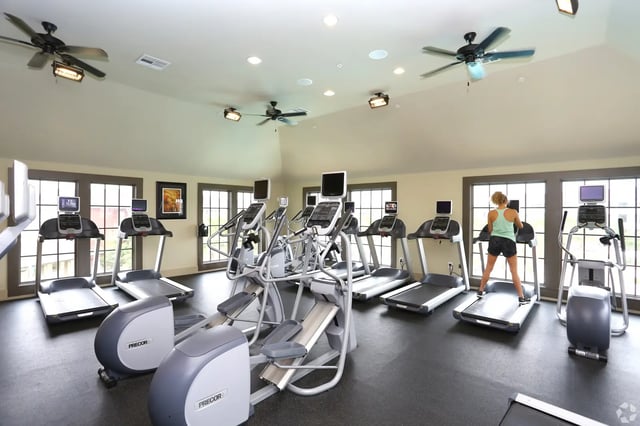 Treadmills ellipticals and person exercising gym at The Cottages of College Station in College Station Student Accommodation