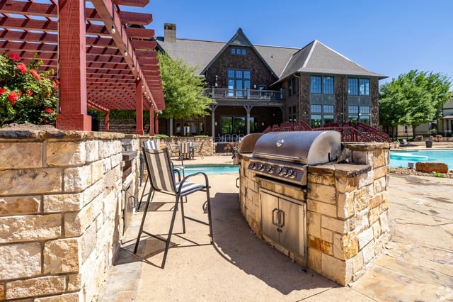 Grill and chairs by pool building exterior at The Cottages of College Station in College Station Student Accommodation