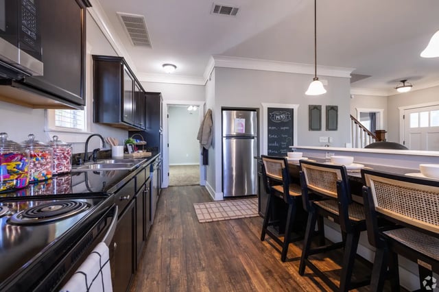 Stainless steel fridge black cabinets bar seating kitchen at The Cottages of College Station in College Station Student Accommodation