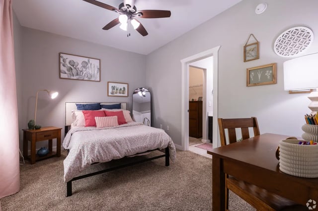 Bed with pink floral duvet desk with pencils bedroom at The Cottages of College Station in College Station Student Accommodation