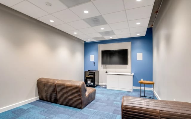 Brown leather sofas large television blue wall living room at Nine East 33rd Apartments in Baltimore Student Accommodation