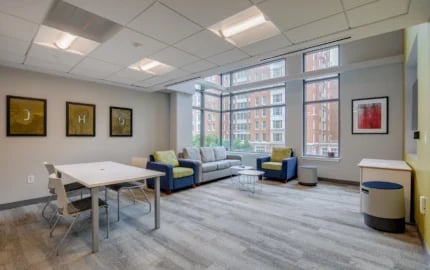 Table chairs sofas artwork windows living room at Nine East 33rd Apartments in Baltimore Student Accommodation