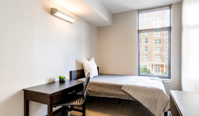 Bed desk chair and plant Bedroom at Nine East 33rd Apartments in Baltimore Student Accommodation