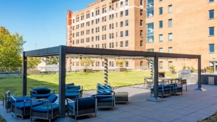 Blue lounge seating under pergola with building exterior at Nine East 33rd Apartments in Baltimore Student Accommodation